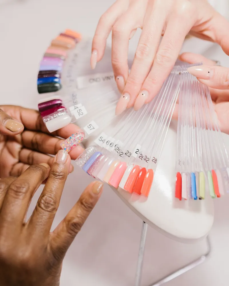 Mains choisissant une teinte dans un nuancier de vernis